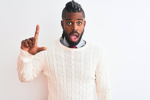 African american man with braids wearing white sweater over isolated white background pointing finger up with successful idea. Exited and happy. Number one. - Foto, Bild