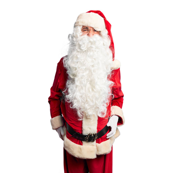 Ein gutaussehender Mann mittleren Alters in Weihnachtsmann-Kostüm und Bart steht wütend und verrückt schreiend frustriert und wütend und schreit vor Wut. Wut und aggressives Konzept. - Foto, Bild