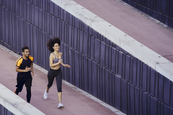 latin young woman and black sports man running - Foto, afbeelding