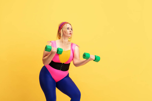 Young caucasian plus size female models training on yellow background - 写真・画像