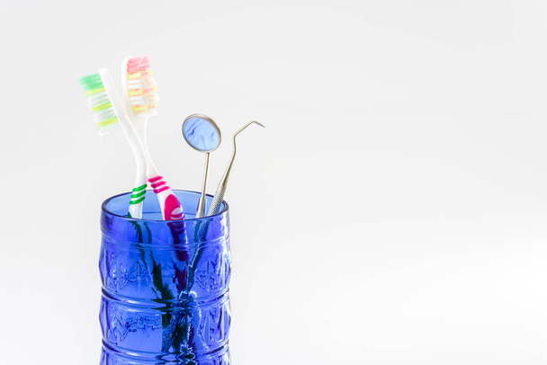 Οδοντόβουρτσες σε ποτήρι και σετ οδοντιατρικής φροντίδας απομονωμένες σε λευκό βα - Φωτογραφία, εικόνα
