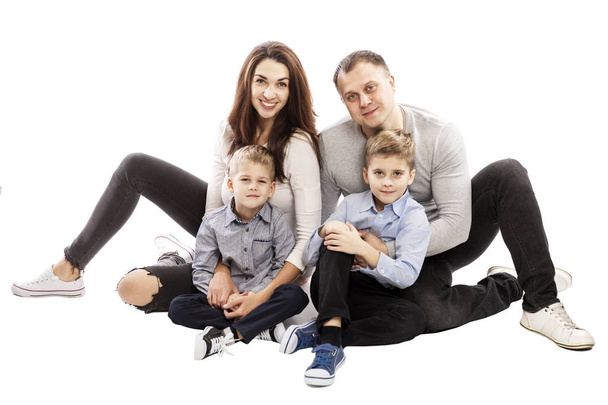 Happy family with two sons are sitting on the floor. Isolated over white background. - 写真・画像