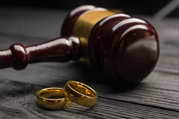Концепция развода и развода. Два золотых обручальных кольца, судья молоток
 - Фото, изображение