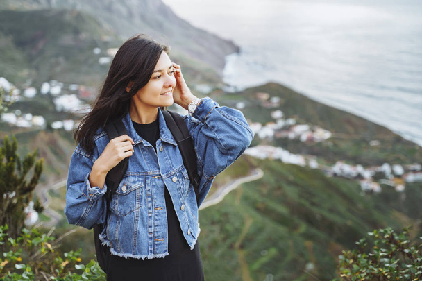 Happy smiling woman with backpack on the background of the ocean and mountains. Travel and lifestyle concept - Фото, зображення