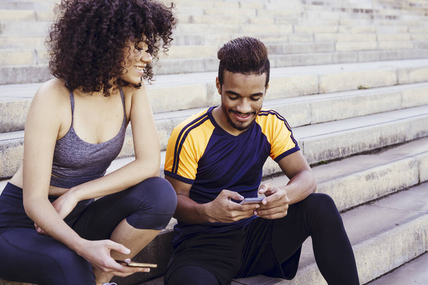 athletic interracial couple having fun with phone - Photo, Image
