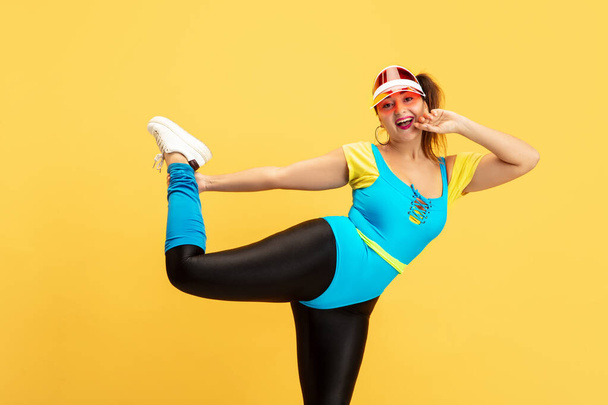 Young caucasian plus size female models training on yellow background - Фото, изображение