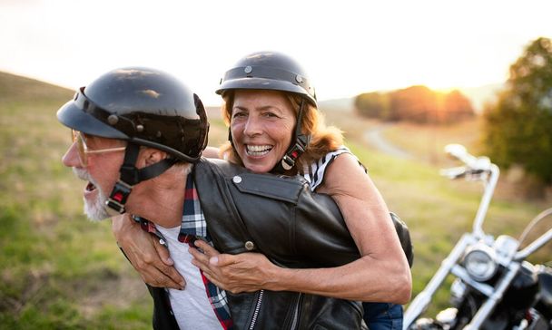 A cheerful senior couple travellers with motorbike in countryside. - Foto, immagini