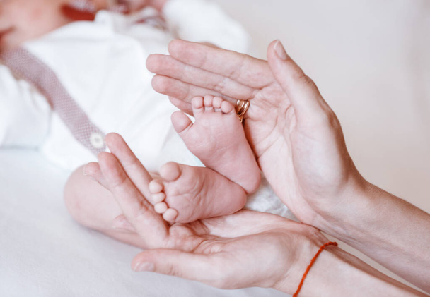 Newborn Baby's feet on female hands closeup. - Fotoğraf, Görsel