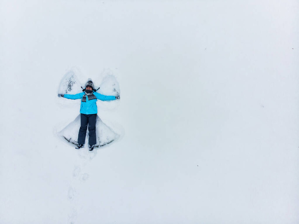 オーバーヘッドビュー女性雪の天使を作る - 写真・画像
