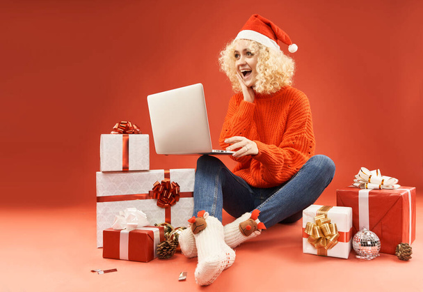 Blondes Mädchen mit Laptop umgeben von Geschenkboxen  - Foto, Bild