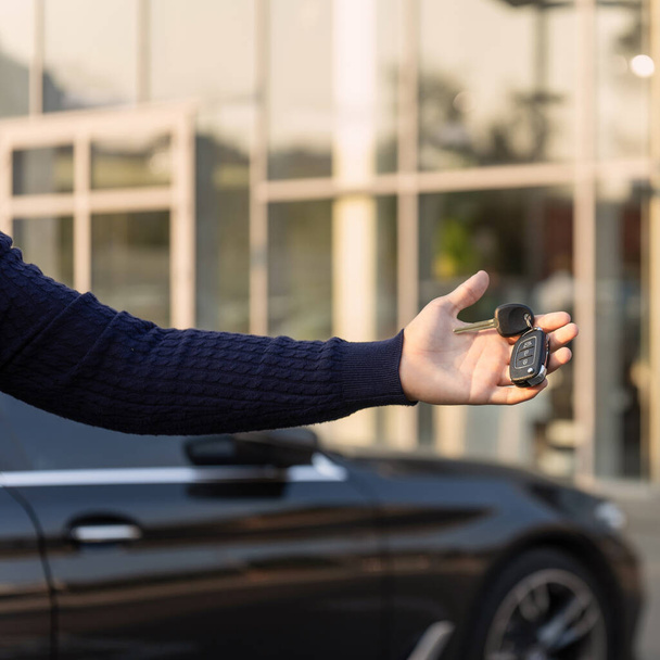 Hand with keys from a luxury car on the background of the showroom - 写真・画像