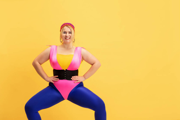 Young caucasian plus size female models training on yellow background - 写真・画像