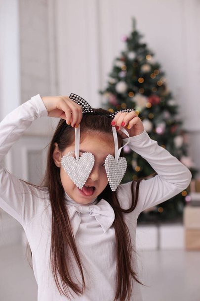 Retrato de Natal de uma menina bonita com longos cabelos loiros em um humor brincalhão retrata emoções diferentes
 - Foto, Imagem