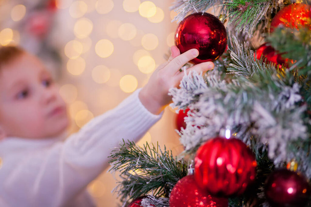 Boy in a white sweater decorated Christmas tree. - Zdjęcie, obraz