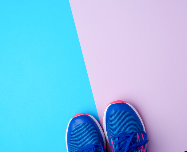 paar sportschoenen met blauwe veters op een gekleurde abstracte ba - Foto, afbeelding