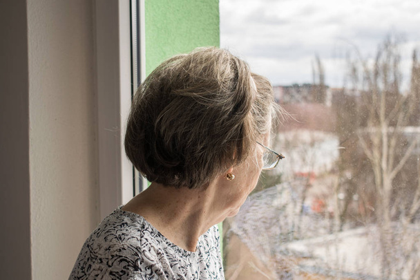  szomorú magányos idős nő néz az ablak mellett egyedül depressziós elhagyatott - Fotó, kép