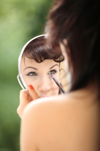 girl retro style applying make up looking at mirror indoor - Фото, изображение