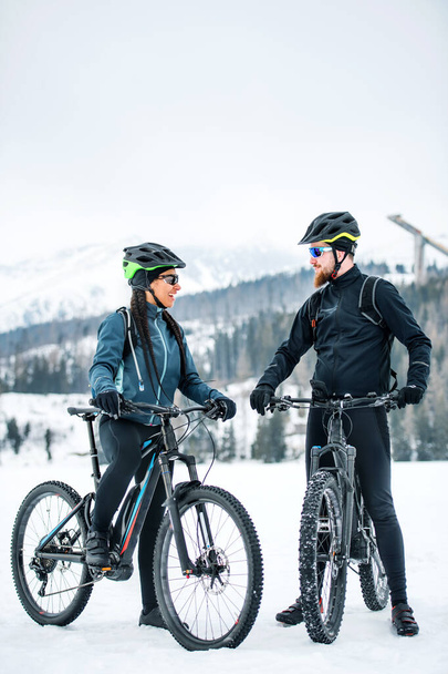 Two mountain bikers with bicycles resting outdoors in winter. - Zdjęcie, obraz