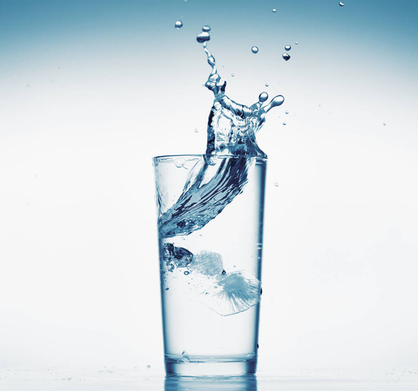 ein Glas Wasser mit Spritzwasser aus fallenden Eiswürfeln, weißer Hintergrund, isoliertes Objekt - Foto, Bild