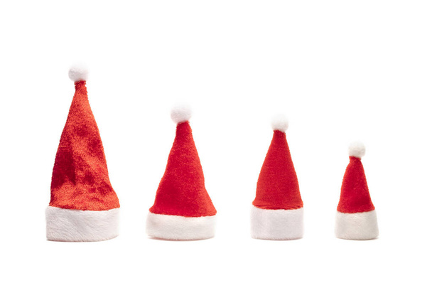 Set of red Santa Claus hats on white background. Family New Year and Christmas holidays. Four souvenir isolated caps with raised bells. Copy space. - Fotoğraf, Görsel