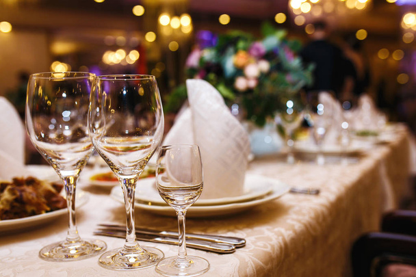 Serving wedding table. Sparkling glassware stands on long table prepared for wedding dinner. Banquet.  - 写真・画像