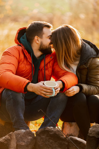 Stylish couple with cup of coffee near bonfire - Photo, Image