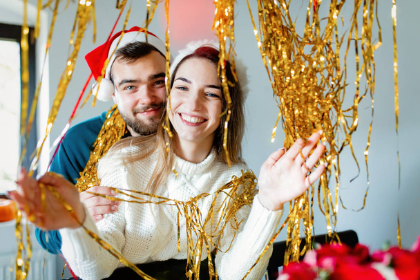 jong paar in kerst hoeden versiert het huis voor Kerstmis - Foto, afbeelding