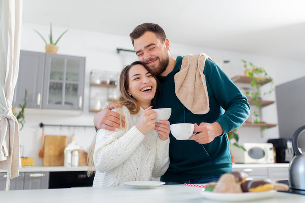 young married couple drinks coffee in the kitchen - Photo, Image