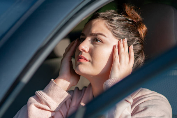 Όμορφη νεαρή γυναίκα οδηγός κάνει μακιγιάζ στον καθρέφτη του αυτοκινήτου. - Φωτογραφία, εικόνα