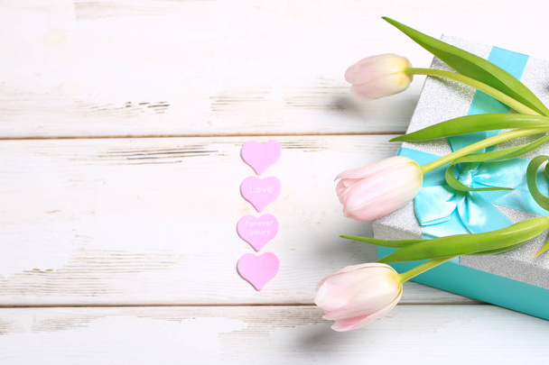pink tulips on a gift box on a white wooden table - Foto, imagen