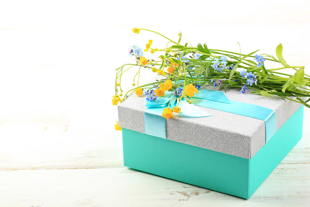 wild flowers on gift box on white wooden background - Foto, imagen