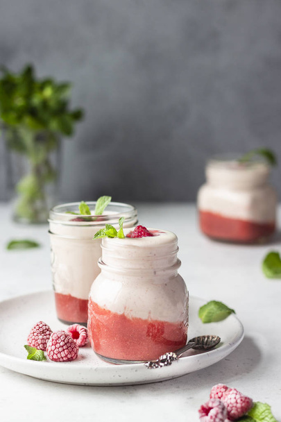Healthy layered raspberry and yogurt smoothie or cocktail in mason jar with fresh berries and mint. Well being and weight loss concept. Natural detox. - Foto, Bild