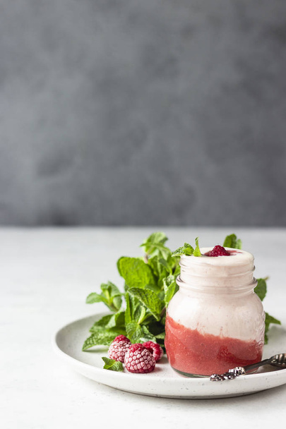 Healthy layered raspberry and yogurt smoothie or cocktail in mason jar with fresh berries and mint. Well being and weight loss concept. Natural detox. - Fotó, kép