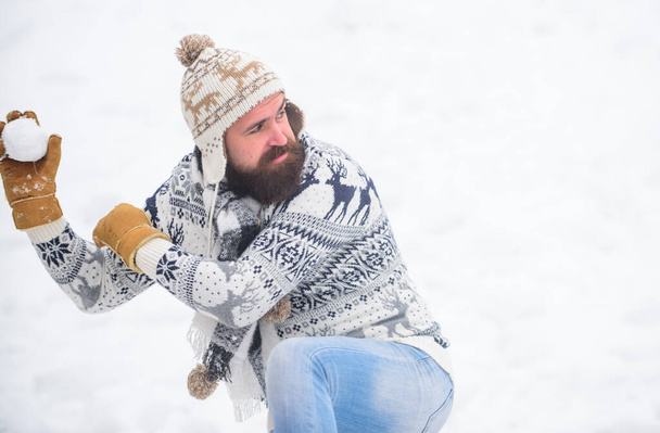 Making snowball. Happiness concept. Smiling man snow background. Snow games. Have fun winter day. Cheerful bearded hipster knitted hat and warm gloves play with snow outdoors. Christmas holidays - Foto, Imagem