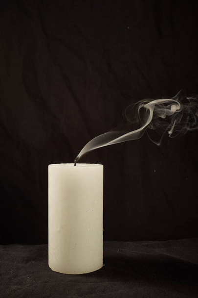 Extinct candle and smoke on a black background. - Фото, изображение