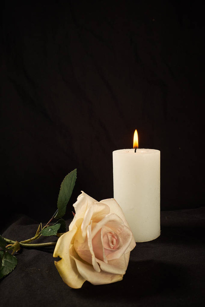 Vela ardente e uma bela rosa em um fundo preto
 - Foto, Imagem