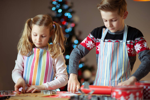 Happy siblings children preparing Christmas cookies at home with - Fotó, kép