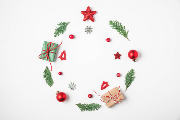 Corona de Navidad hecha de ramas de abeto, decoraciones rojas, cajas de regalo, conos de pino sobre fondo blanco
 - Foto, Imagen