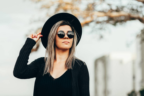 Outdoor portrait of woman wearing fedora hat and sunglasses - Foto, Bild