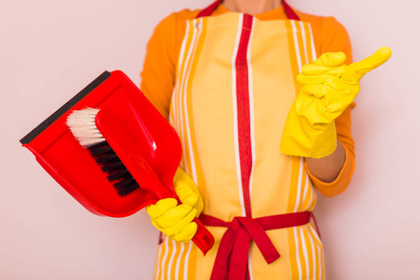 Image of housewife holding dustpan and  scolding. - Foto, afbeelding