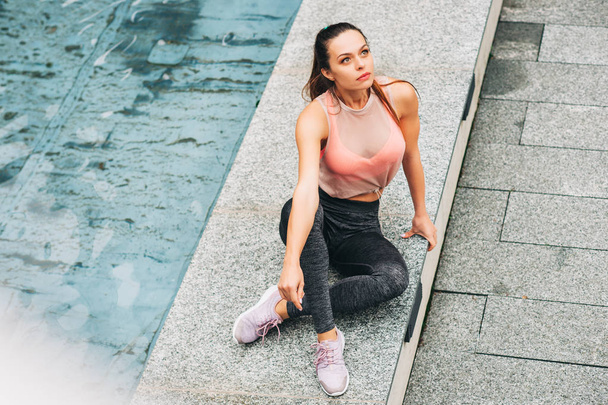 Outdoor portrait of young beautiful fit woman, wearing fashionable activewear, athlete model posing in urban background, sport fashion - 写真・画像