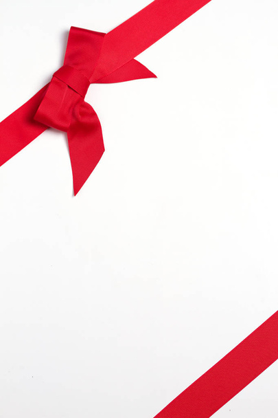 Layout made of red ribbon bow on white background. Mockup, flat lay. View from above, top, vertical image - Foto, Bild