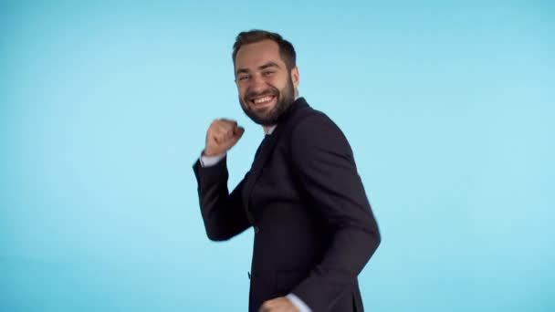 Surprised excited happy businessman funny dancing on blue background. Man shows yeah gesture of victory, he achieved result, goals.  - Materiał filmowy, wideo