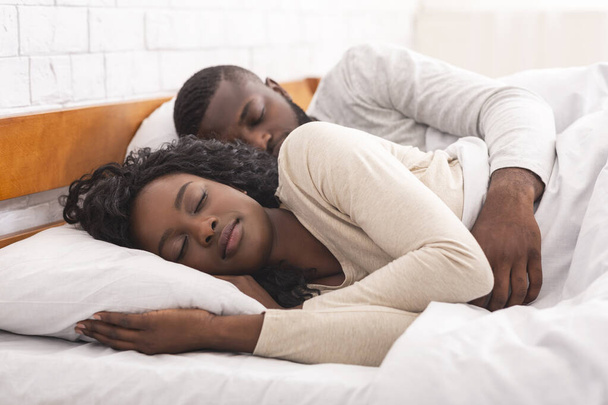 Afro casal dormindo juntos em cama confortável em casa
 - Foto, Imagem
