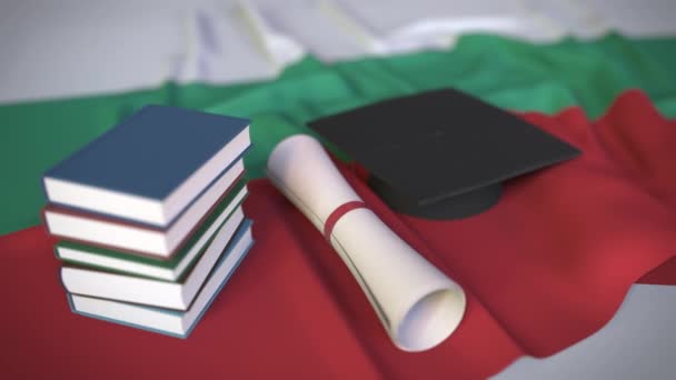 Ballagási sapka, könyvek és oklevelek a bolgár zászlóról. Felsőoktatás Bulgáriában kapcsolódó koncepcionális 3D animáció - Felvétel, videó
