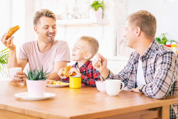 Happy young fathers and son have breakfast in the kitchen, gay f - Foto, imagen