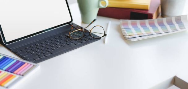Schnappschuss eines modernen Grafikdesignerarbeitsplatzes mit leerem Bildschirm, digitalem Tablet mit Bürobedarf und Kopierraum auf weißem Tisch  - Foto, Bild