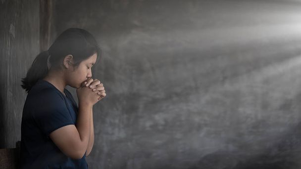 Menina enquanto reza por religião cristã com borrado de seu bo
 - Foto, Imagem