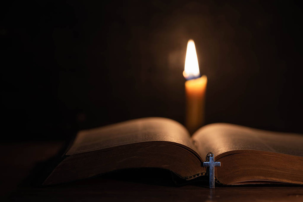 Cruz con biblia y vela sobre una vieja mesa de madera de roble
.  - Foto, Imagen