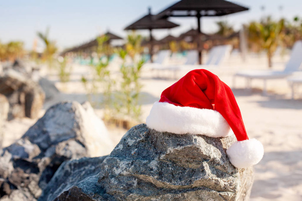 Καπέλα Αϊ-Βασίλη στην παραλία. Χριστούγεννα και Πρωτοχρονιά διακοπές στην έννοια των θερμών χωρών. - Φωτογραφία, εικόνα